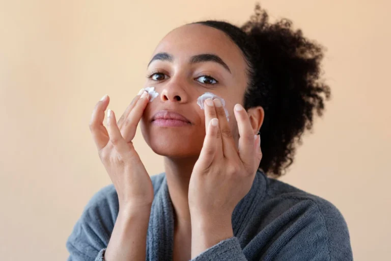 Mulher aplicando creme na pele do rosto, cuidando da rotina de skincare para uma pele mais saudável e bonita com a Bella Femme.