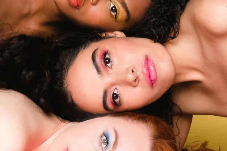 Três mulheres com diferentes estilos de maquiagem.