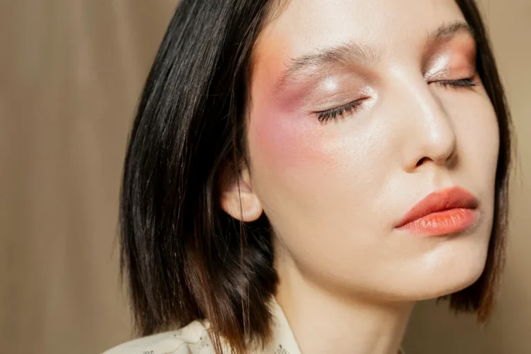 Close no rosto de uma mulher com maquiagem suave e iluminada, com destaque para tons rosados e dourados na pele, sugerindo cores da primavera em um editorial de beleza