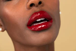 Close-up de boca com maquiagem para a boca, como lábios vermelhos e brilho, destacando a beleza do make up. Imagem realçando detalhes de maquiagem e estilo.