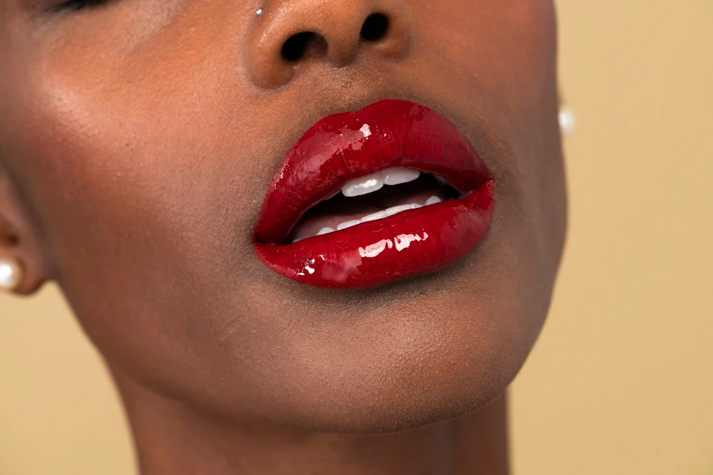 Close-up de boca com maquiagem para a boca, como lábios vermelhos e brilho, destacando a beleza do make up. Imagem realçando detalhes de maquiagem e estilo.