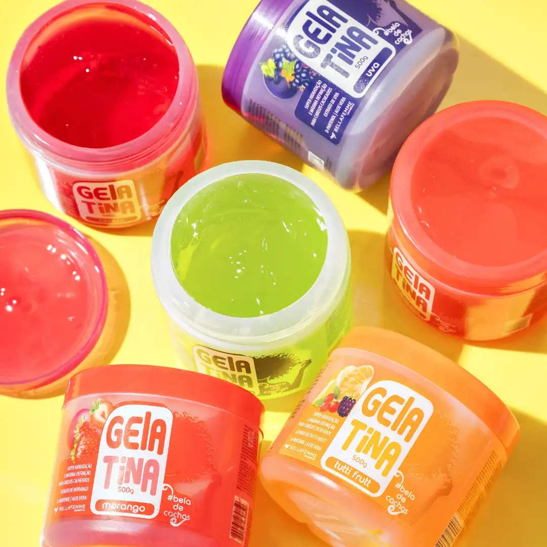 Diversas embalagens de produtos para cabelo, como gelatina colorida em potes diferentes sobre fundo amarelo, destaque para várias cores como vermelha, verde, laranja e rosa.