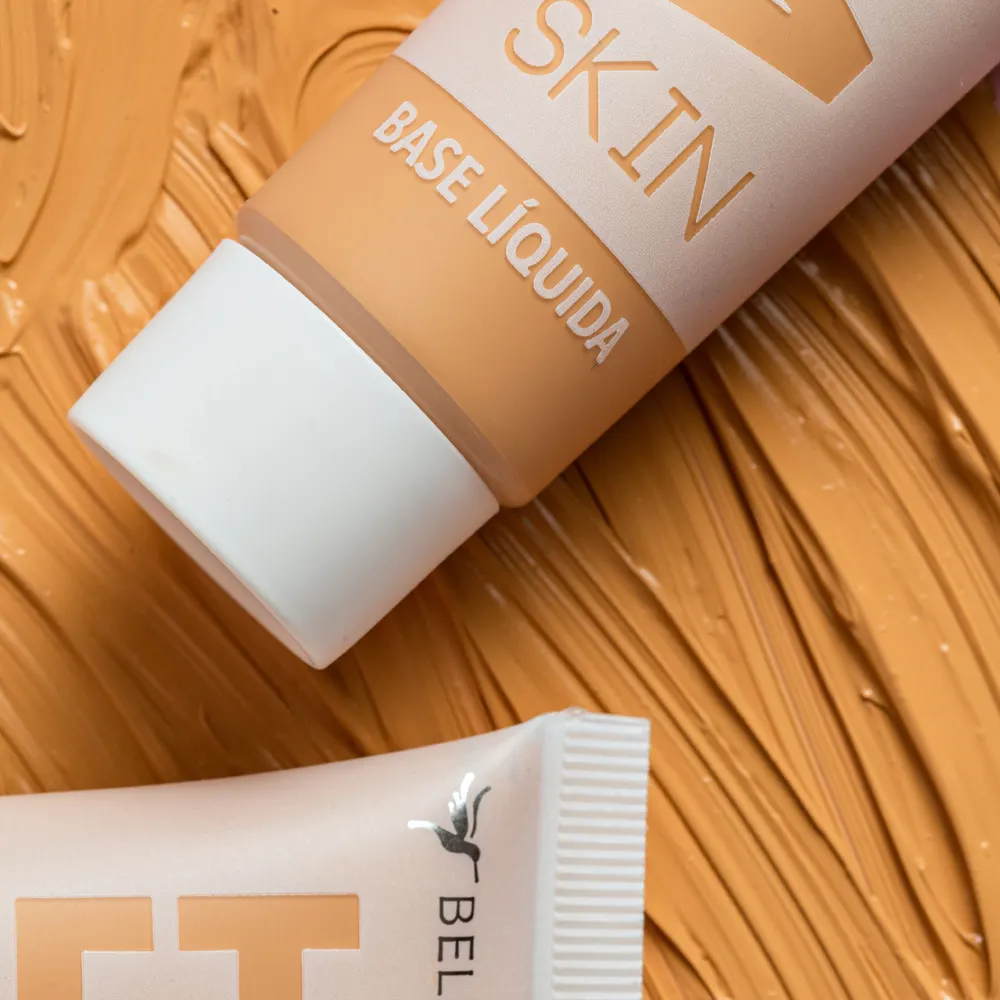 Base Liquida em embalagem branca e dourada, com textura de madeira ao fundo, destaque para o rótulo “SKIN” e “BASE LIQUIDA” cores médias