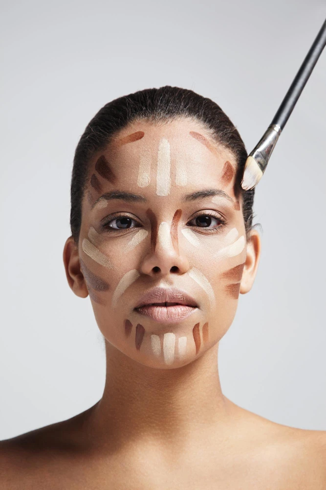 Maquiagem para o rosto Bella Femme com aplicação de base em formato de pinceladas no rosto, usando contornos e clareamento para destacar maçãs, testa e queixo
